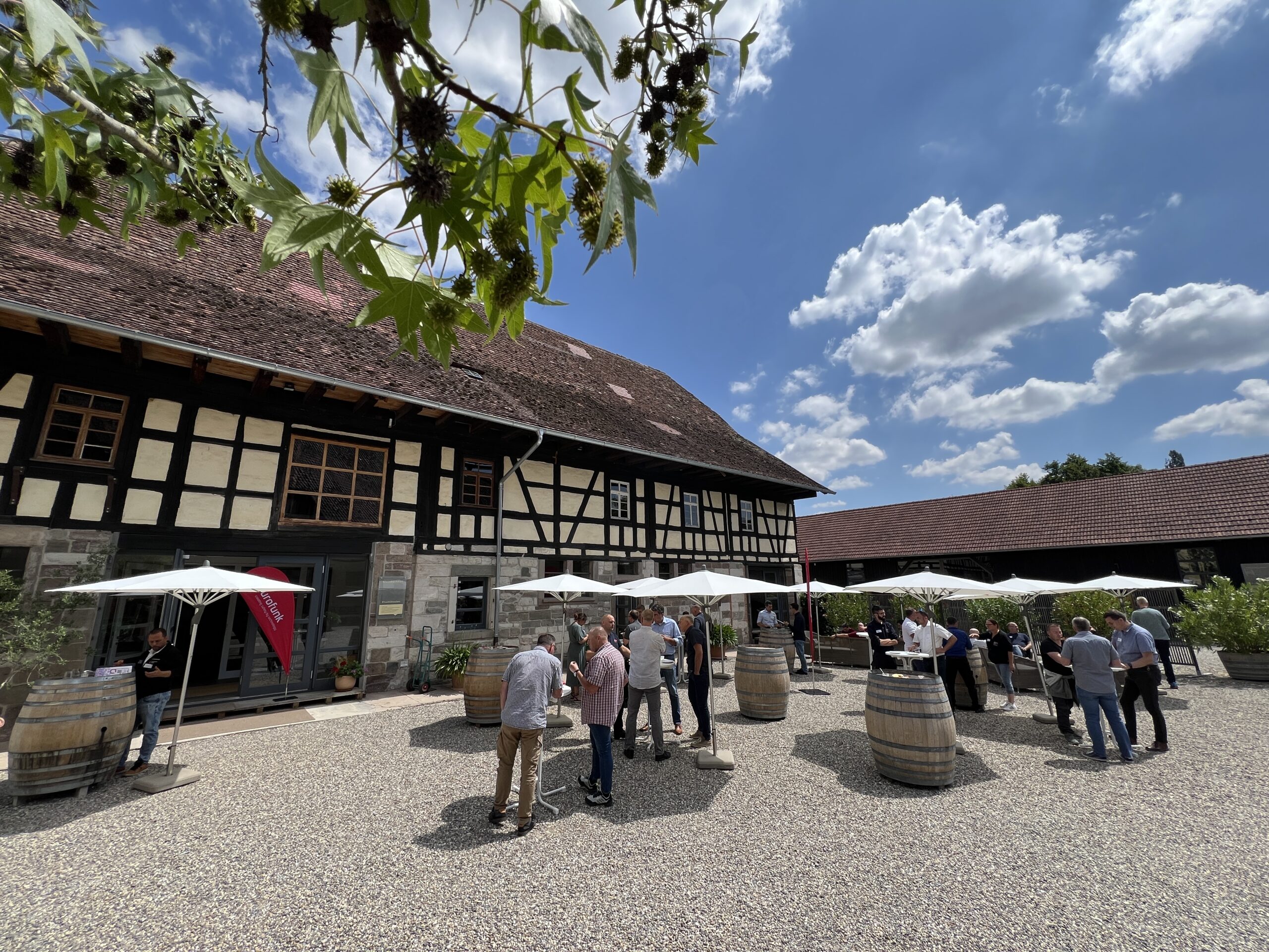 Blauer Himmel. Sonne. Menschen stehen unter Schirmen im Schatten.