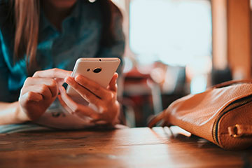 Frau hält Smartphone Cafe